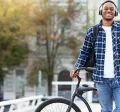 Smiling young man wearing headphones and leaning against his bike.